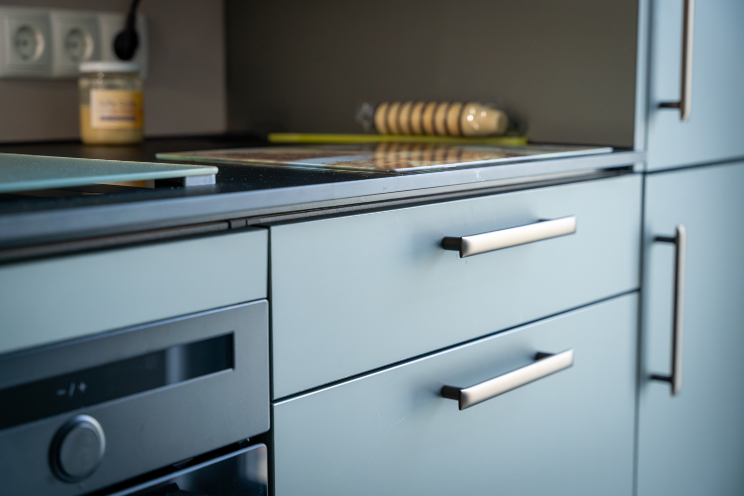 Detailaufnahme der maßgefertigten Küchenmöbel mit hochwertigen Fronten und modernen Griffen im Aufenthaltsbereich der Bremer GmbH.