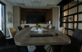 Individuell gefertigter Konferenztisch im Besprechungsraum der Bremer GmbH mit moderner Medienwand und eleganter Raumgestaltung.
