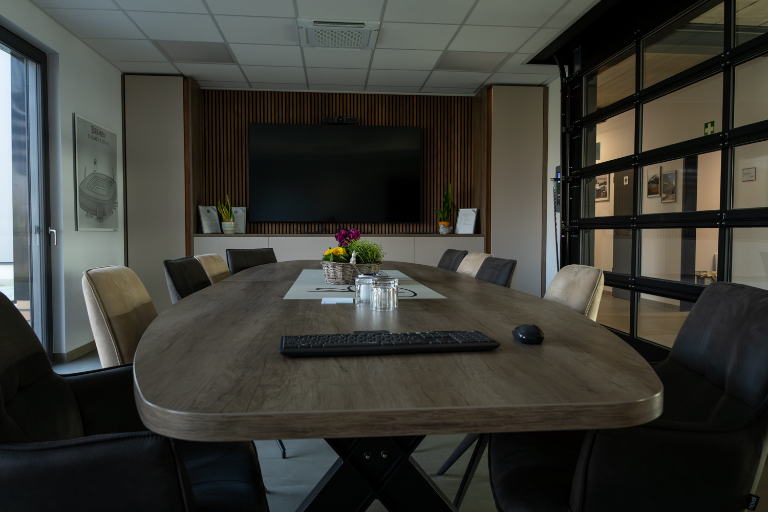 Individuell gefertigter Konferenztisch im Besprechungsraum der Bremer GmbH mit moderner Medienwand und eleganter Raumgestaltung.