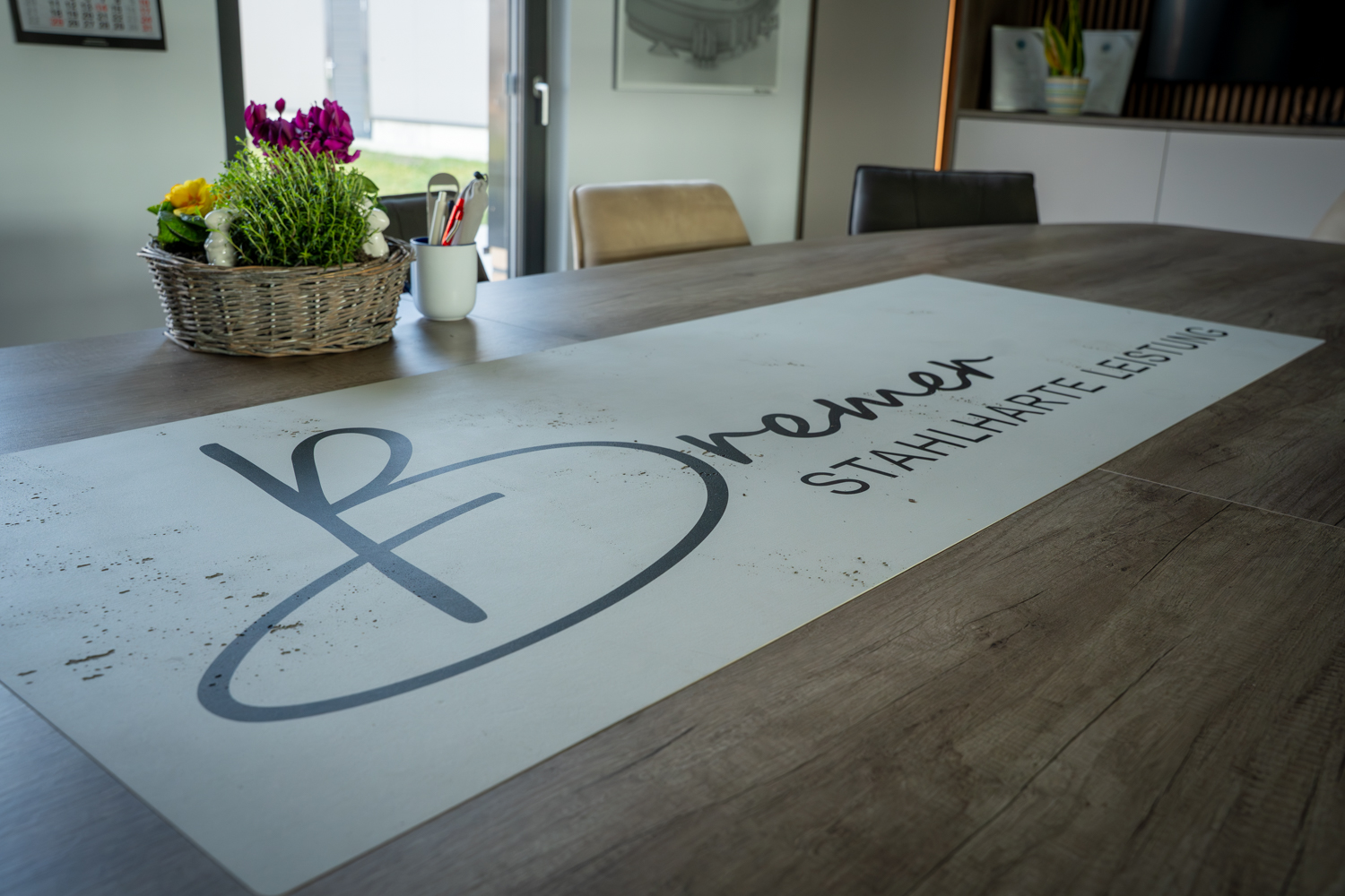 Detailaufnahme des maßgefertigten Besprechungstisches der Bremer GmbH mit integriertem Firmenlogo und hochwertiger Holzoberfläche.